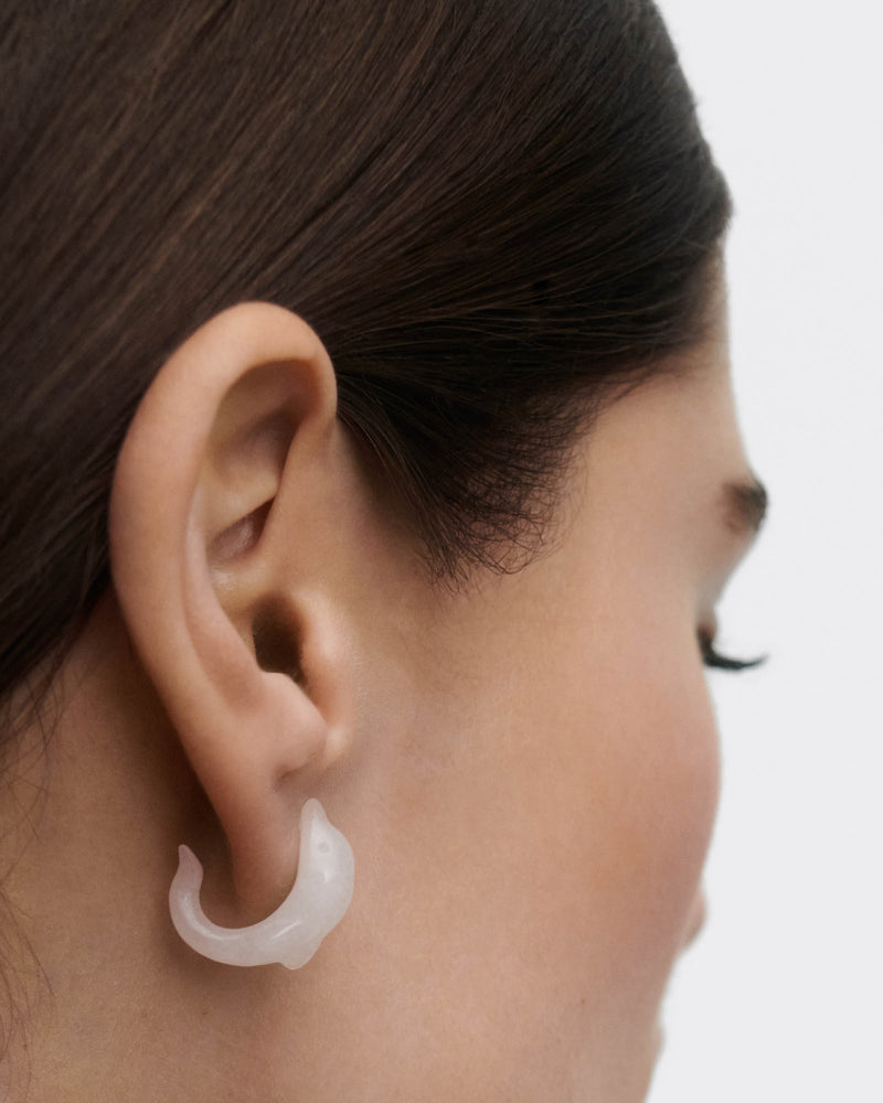 Minimalist dolphin ear piercing with a hand-sculpted white gemstone